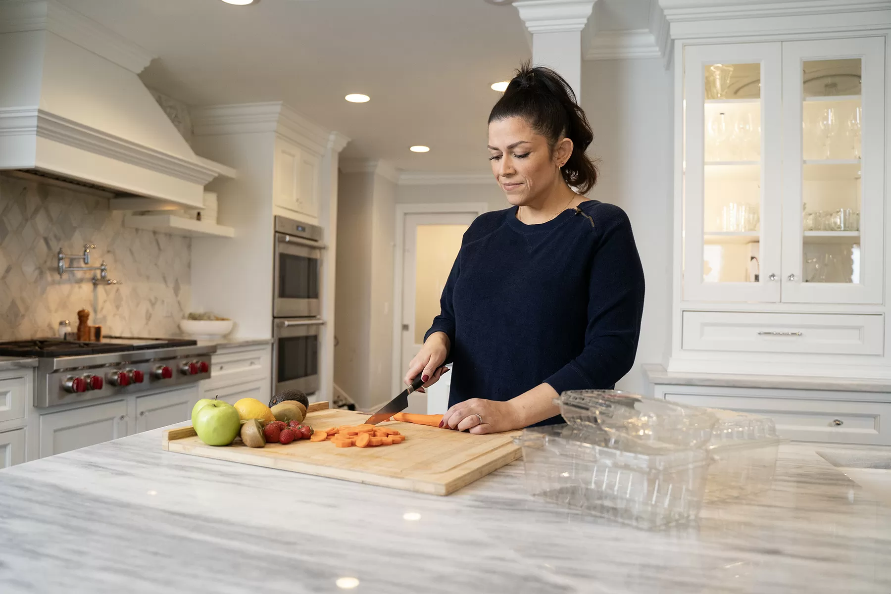 woman chopping vegetables in kitchen to put in tupperware - food packaging solutions