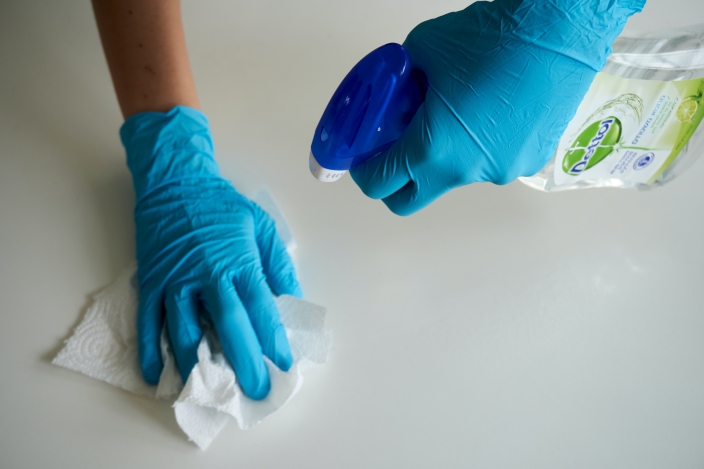 spraying and wiping white surface with gloves on
